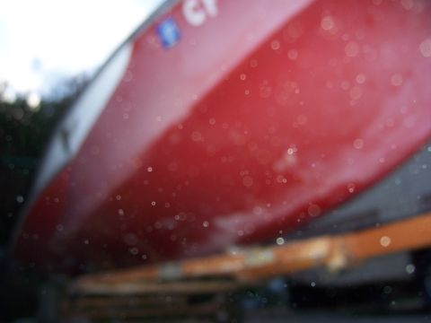 1991 Ford Bronco - A close-up of a red boat hull with a white stripe, partially obscured by water droplets.