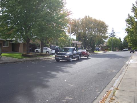1991 Ford Bronco - A black pickup truck, likely a 1995 model, is seen towing a small red boat down a suburban street.
