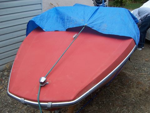 1991 Ford Bronco - Boat covered with a blue tarp, parked outside near a building.