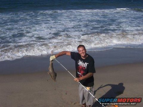1991 Ford Bronco - Man proudly displays his catch on a sandy beach with ocean waves.