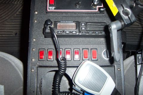 1998 Ford Crown Victoria - Close-up view of a police radio and several red toggle switches inside a vehicle.