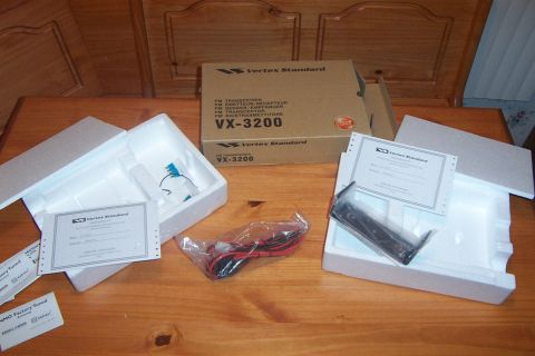 1998 Ford Crown Victoria - Unboxed Vertex Standard VX-3200 FM transceiver with its accessories and paperwork laid out on a wooden surface.