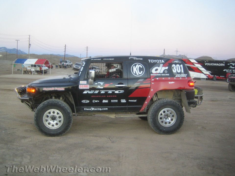 Side view of black and red Toyota FJ Cruiser race truck #301 in a dirt lot