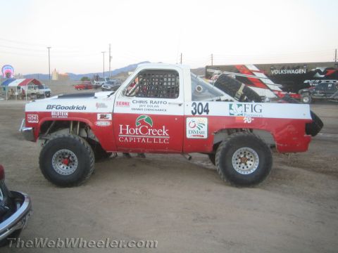 1990 Ford Bronco - red and white number 304 off-road race truck with Hot Creek Capital and BFGoodrich graphics on a dirt lot.