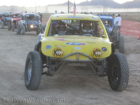 1990 Ford Bronco - Front view of a yellow tube-frame off-road race buggy with K&N decals and two helmeted occupants on a dirt track.
