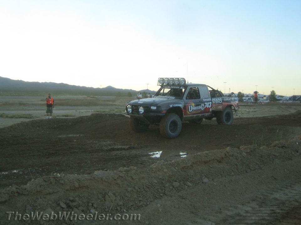 Black off-road race truck with #743 markings parked on a dirt track at dusk