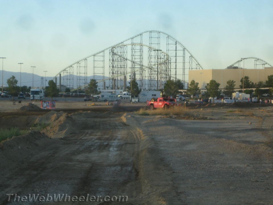 Dirt track with a red truck and a roller coaster in the background