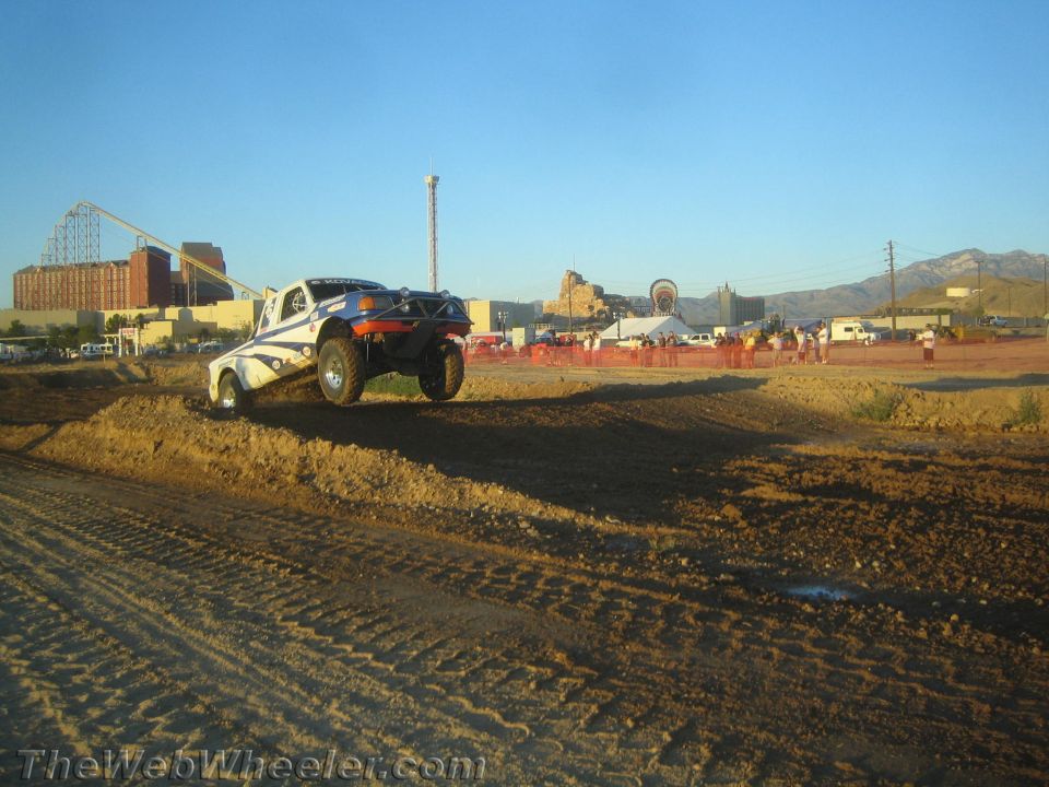 White off-road buggy cresting a dirt berm under a blue sky