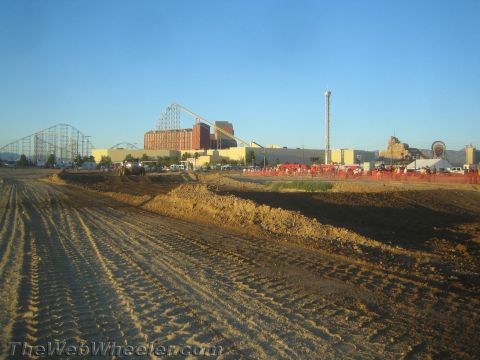 1990 Ford Bronco - wide graded dirt off-road course stretches toward buildings, a tower ride and a roller coaster.