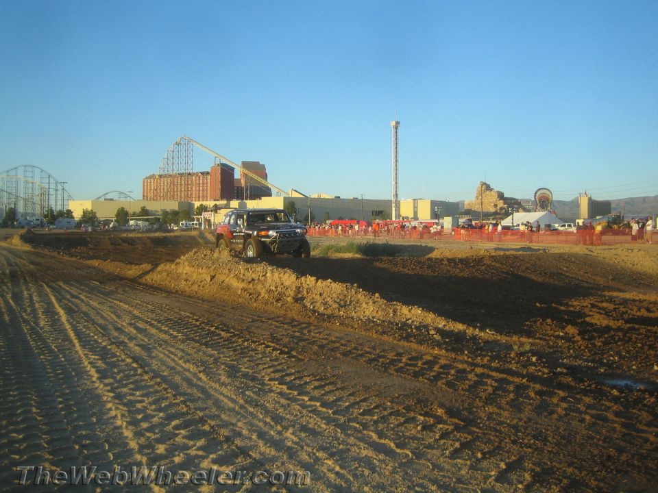 Dark pickup truck on a dirt berm under a clear blue sky