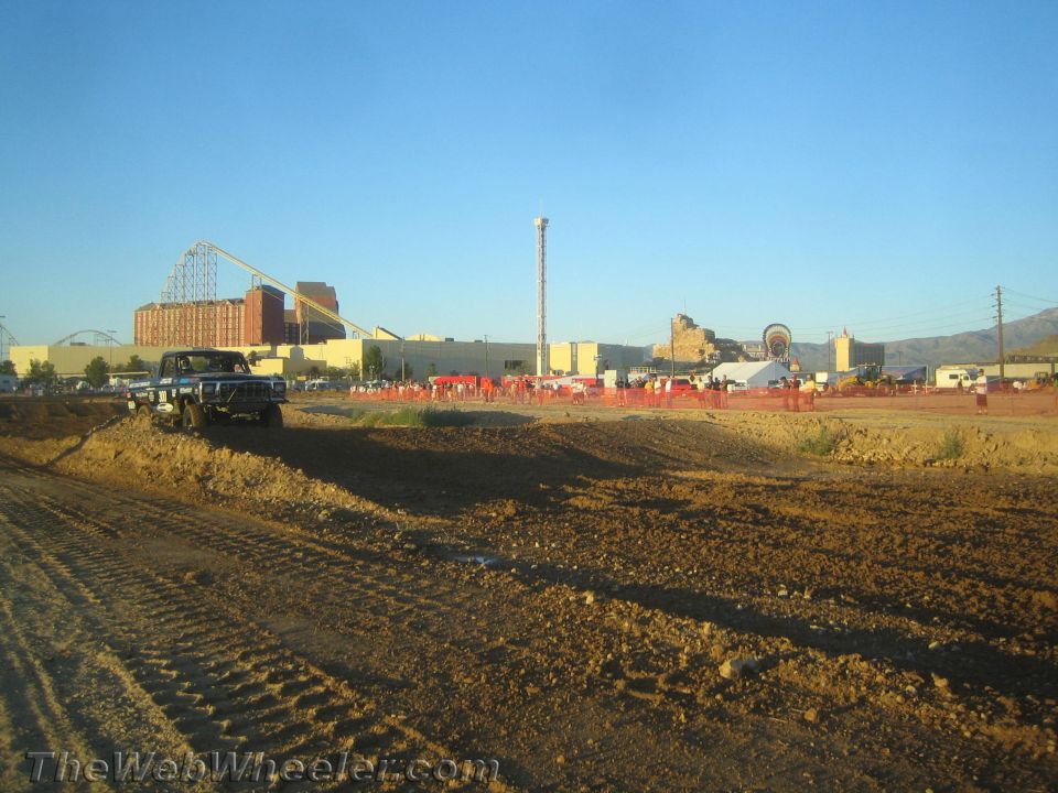 Dirt off-road race course with a dark pickup at left and roller coaster beyond