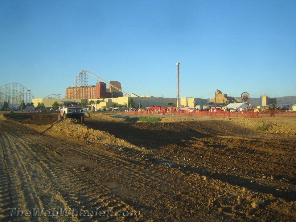 Dirt off-road course with a light pickup at left and roller coaster behind