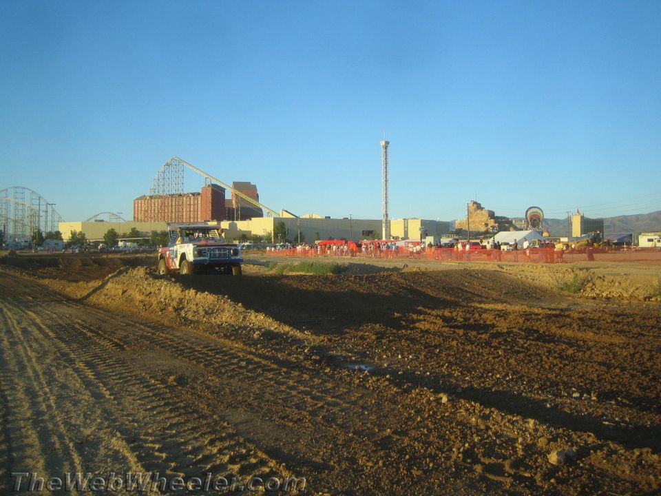 White flatbed-style truck on a dirt off-road course at golden hour