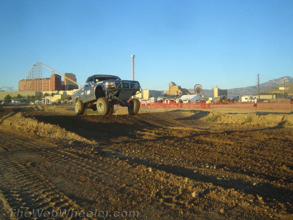 Lifted off-road pickup truck jumping over a dirt berm at an outdoor course