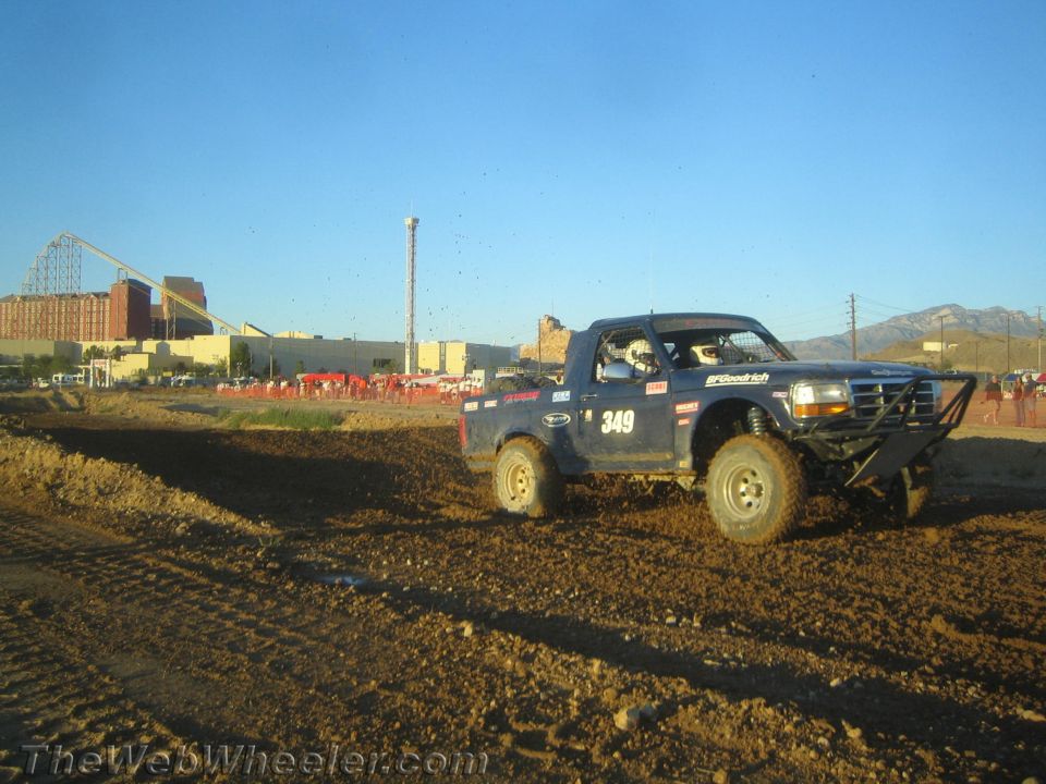 Blue number 349 off-road pickup truck on a dirt course at dusk