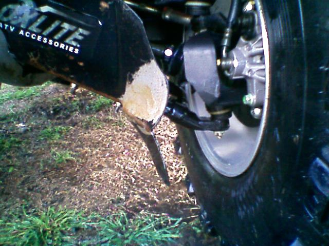 Damaged black CV guard skid plate beside front brake rotor and caliper