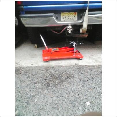 1995 Dodge 1500 - Blue pickup truck rear with a skull hitch cover and a red floor jack on the ground.
