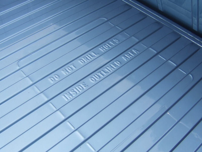 Blue-gray ribbed truck bed floor with embossed text: Do Not Drill Holes Inside Outlined Area