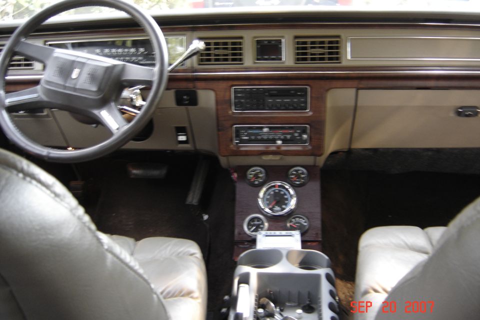 Interior shot of a car's dashboard, steering wheel, and center console with aftermarket gauges