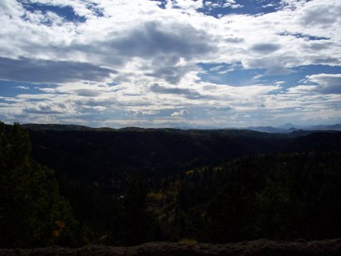 1972 Ford Ranchero - A vast landscape under a dramatic sky, with rolling hills covered in dense forest.