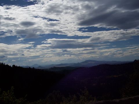 1972 Ford Ranchero - A scenic view of rolling hills covered in dark trees under a dramatic sky filled with clouds.