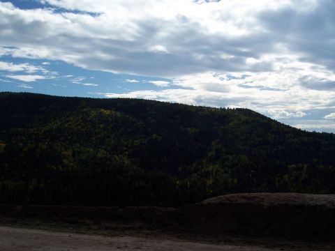 1972 Ford Ranchero - A view of a densely forested mountain range under a dramatic sky with scattered clouds.