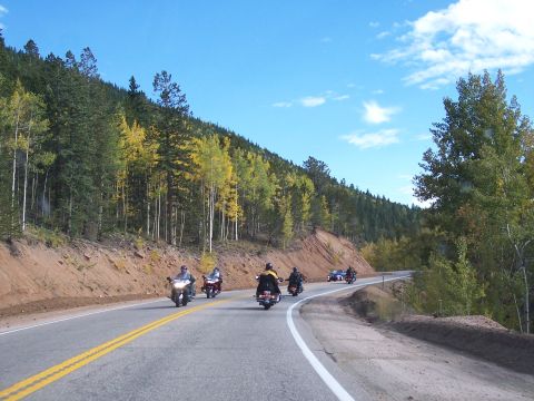 1972 Ford Ranchero - A group of motorcycles and a car travel along a scenic mountain highway during the day.