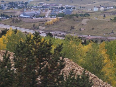1972 Ford Ranchero - A red car travels along a highway, with a small town and colorful autumn foliage visible in the distance.