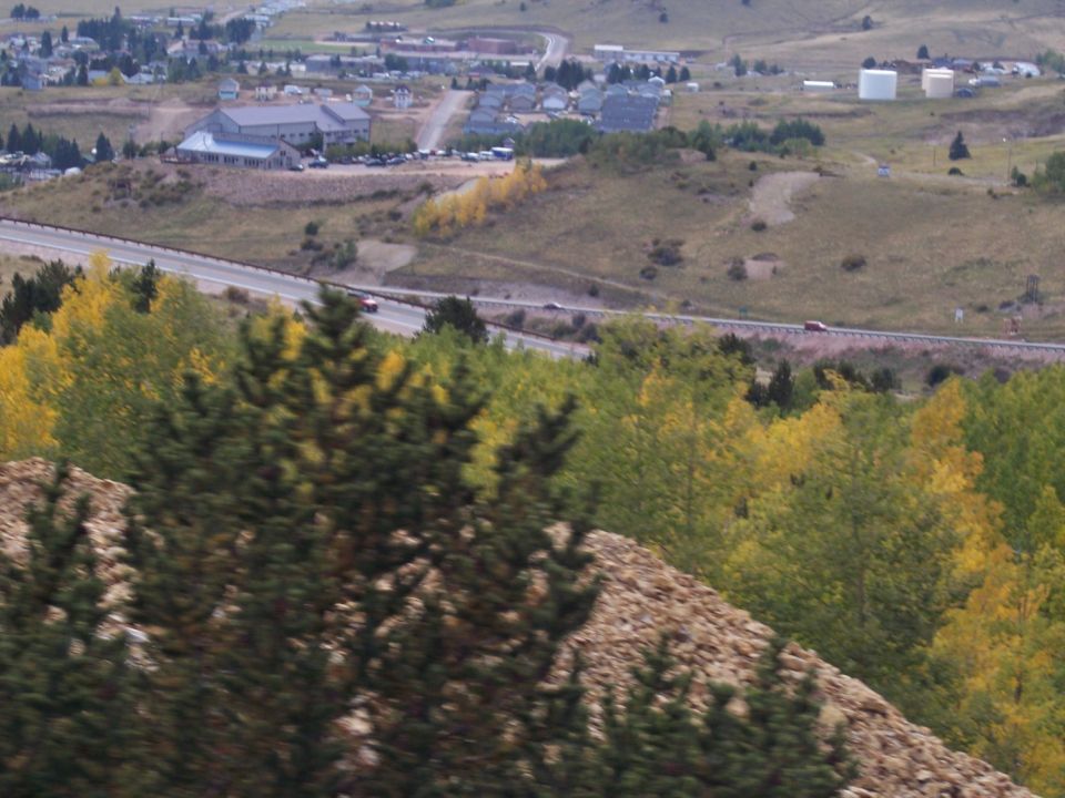 Red car driving on a highway with autumn trees and a town in the background