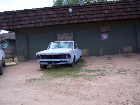 1972 Ford Ranchero - A light blue 1961 Plymouth Valiant sits in front of a garage with an 'Open On' sign.