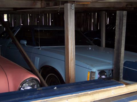 1972 Ford Ranchero - Multiple vehicles are stored inside a wooden structure, with one light blue coupe partially visible.