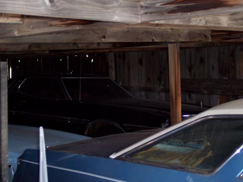 1972 Ford Ranchero - A dark 1972 Ford Ranchero is partially visible inside a barn, alongside other vehicles.