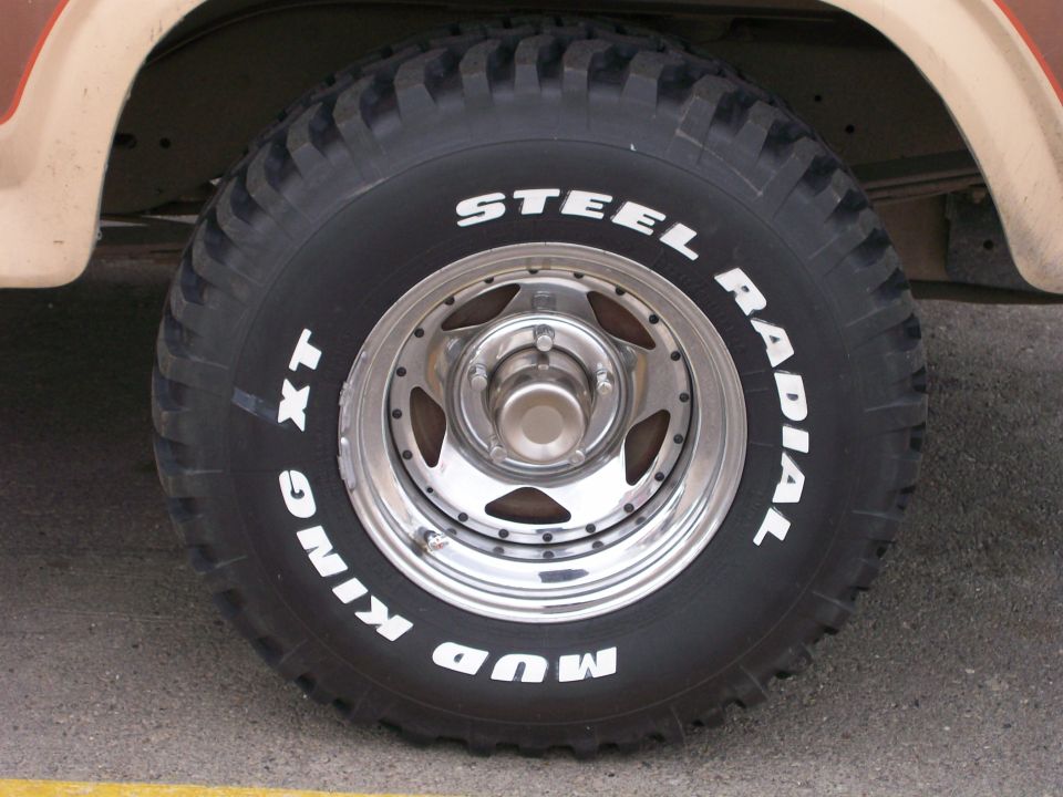 Mud King XT Steel Radial tire on a chrome rim. Part of a vehicle is visible