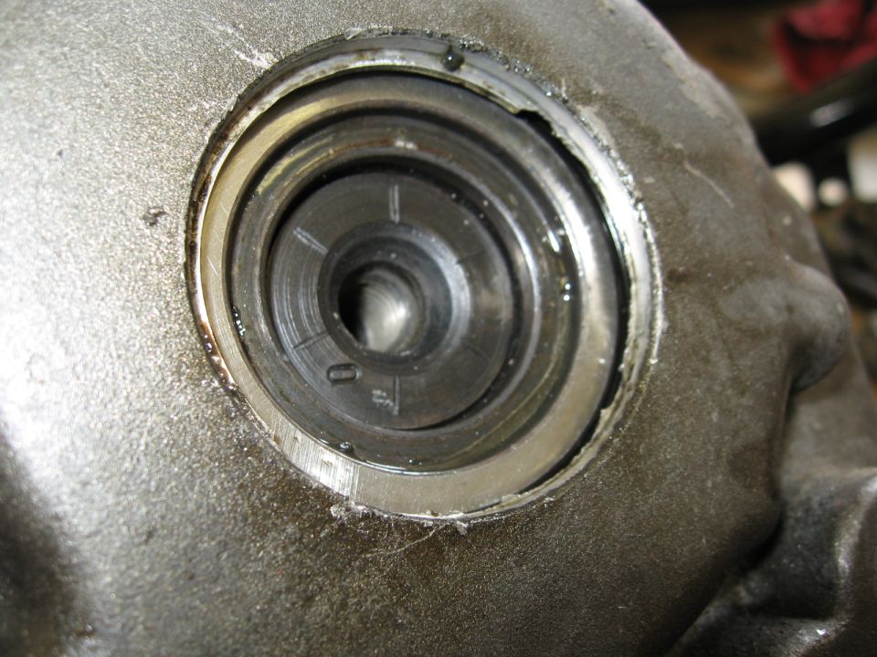 Close-up of a greasy, metallic engine component with circular grooves and some markings