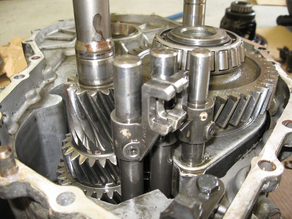 Transmission gears and shafts inside a metal casing, showing wear and oil