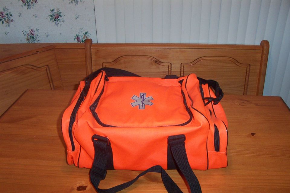 Orange medical bag with black trim and straps, a silver star of life emblem on the front