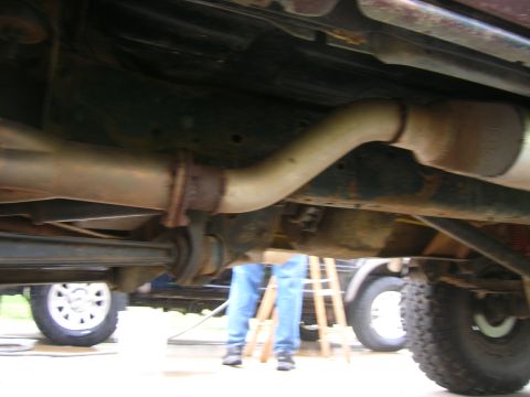 1979 Ford Bronco - The underside of a vehicle, focusing on the exhaust system, with another vehicle partially visible in the background.