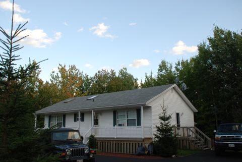 1996 Ford Bronco - A house is seen with two vehicles parked in the driveway under a partly cloudy sky.