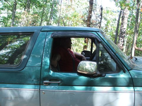1996 Ford Bronco - Side view of a green and silver SUV, possibly a 1996 Ford Bronco, with a driver inside.