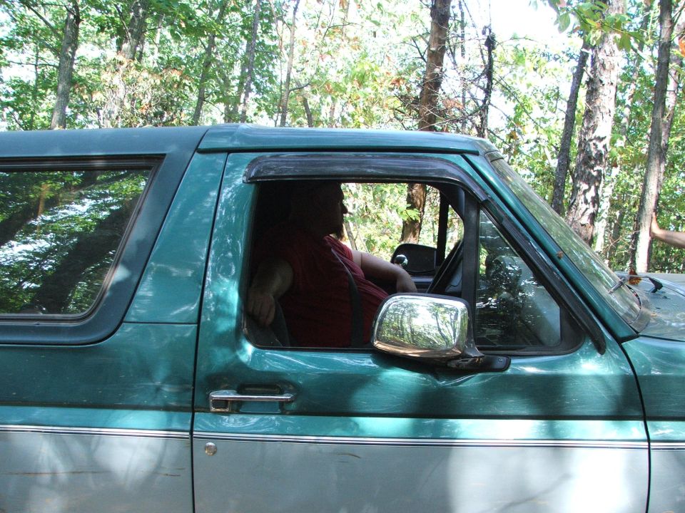Green and silver SUV side view. Driver visible
