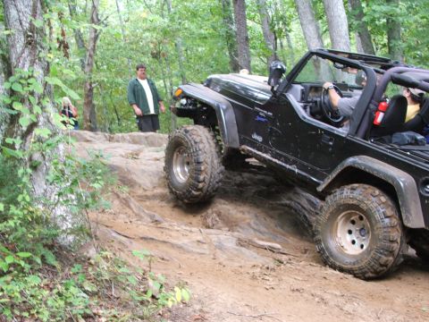 1996 Ford Bronco - Jeep Wrangler navigating a challenging off-road course with steep inclines and large rocks.