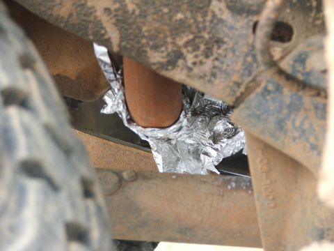 1996 Ford Bronco - A close-up view of a vehicle's undercarriage shows an exhaust pipe crudely wrapped in aluminum foil.