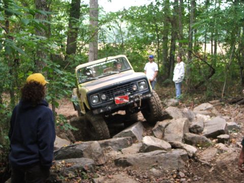 1996 Ford Bronco - A yellow off-road vehicle navigates a rocky trail with spectators watching.