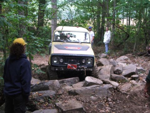 1996 Ford Bronco - Jeep CJ-5 tackles a challenging rocky obstacle on an off-road trail.