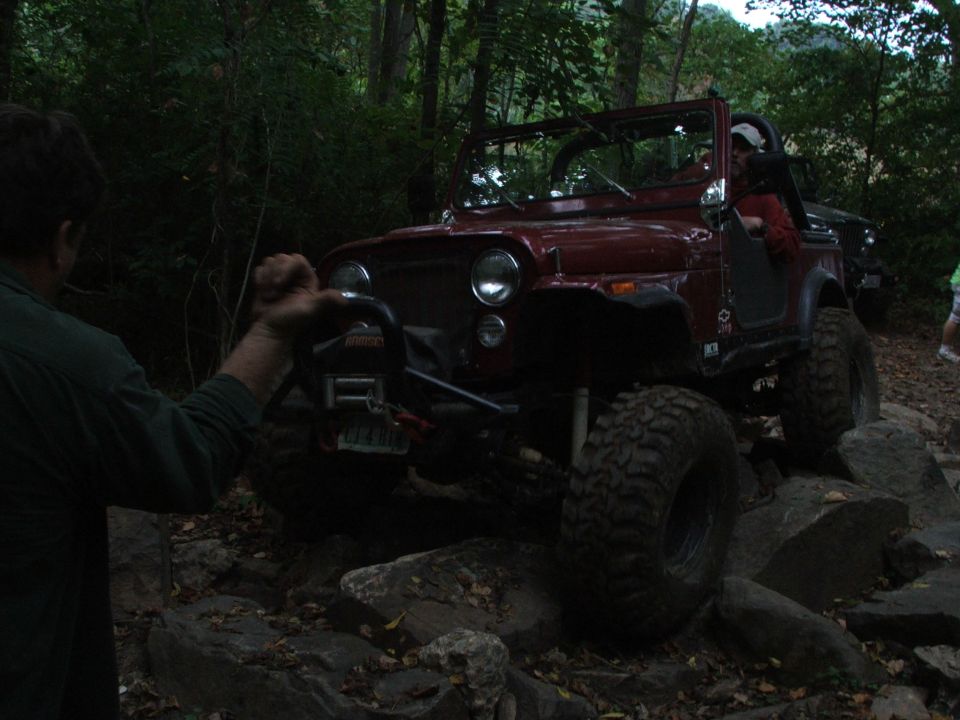 Red off-road jeep with large tires navigating rocky terrain