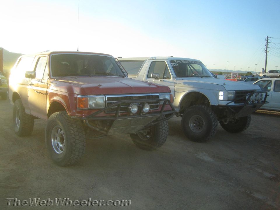 Red lifted SUV with brush guard and light bar parked beside a white SUV