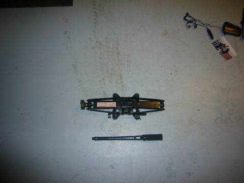 2000 Ford Crown Victoria - A car jack and lug wrench are shown laid out on a flat surface.