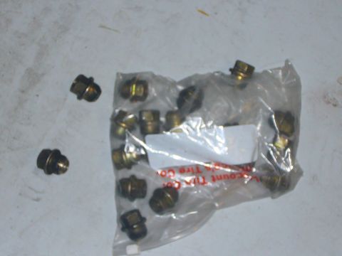 2000 Ford Crown Victoria - A collection of lug nuts, some loose and others packaged, are visible on a light-colored surface.