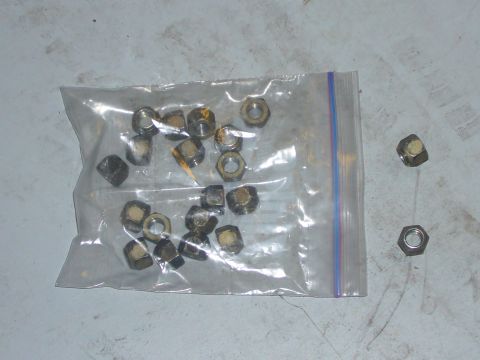 2000 Ford Crown Victoria - A collection of lug nuts, some inside a plastic bag and a few scattered outside, are shown on a textured surface.