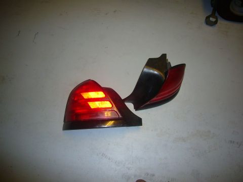 2000 Ford Crown Victoria - A damaged vehicle taillight is shown on a plain surface, with its internal lights still functional.